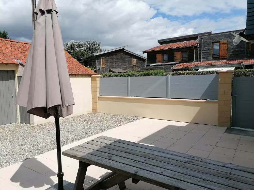 Cour intérieure close avec parasol, table de pique-nique et terrasse dallée