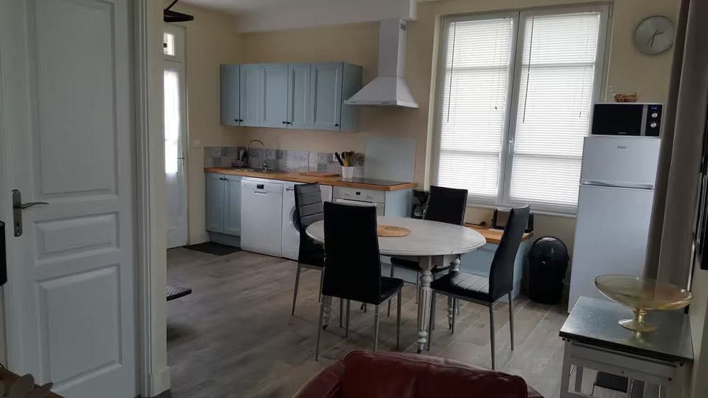 Coin repas de la cuisine équipée, avec hotte, plaques vitrocéramique et table ronde