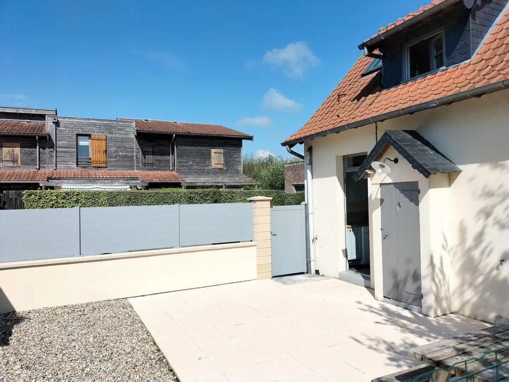 Façade de la maison et portail blanc donnant sur la cour privée du gîte
