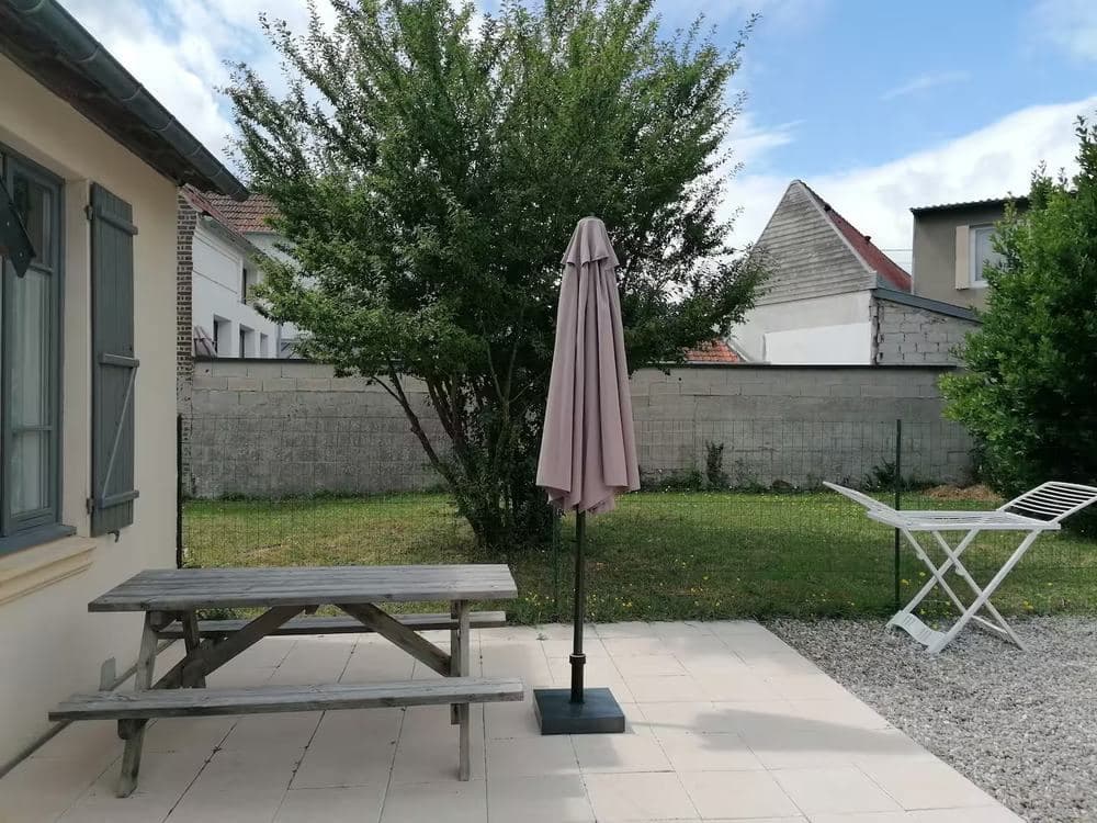 Jardin clos avec pelouse, arbre, table de pique-nique et parasol, à l'arrière de la maison