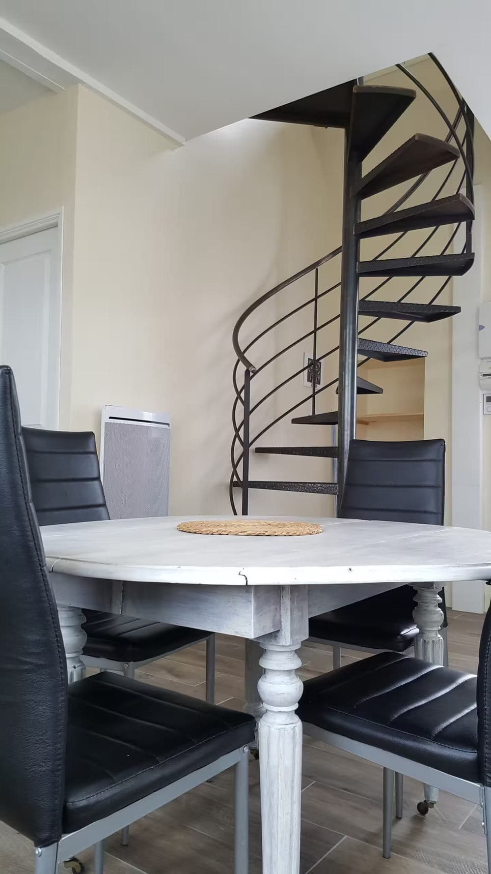 Salle à manger avec table ronde et escalier hélicoïdal menant à l'étage